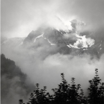 Martha Ceccio - Courmayeur, Italy | Photograph | 30.5" x 30.5""On a day off, I took my camera to the small Italian mountain town of Courmayeur, and was able to capture this image.  Clouds were forming and shifting on the peaks in the distance.  And trees were silhouetted against the light, with branches extending upward."